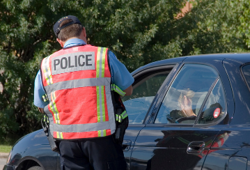 A police officer talks to a driver through the driver side window.