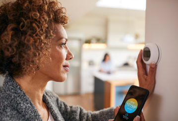 A woman program her smart thermostat with her phone in her home.