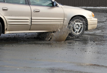 Car driving through pot hole.