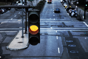 A stoplight turns yellow above a city intersection.